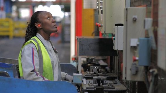 Une ouvrière devant sont outil de travail, une énorme machine.