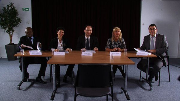 Assis derrière une table, deux femmes et trois homme. Devant eux, un petit écriteau spécifiant leur nom et leur entreprise.