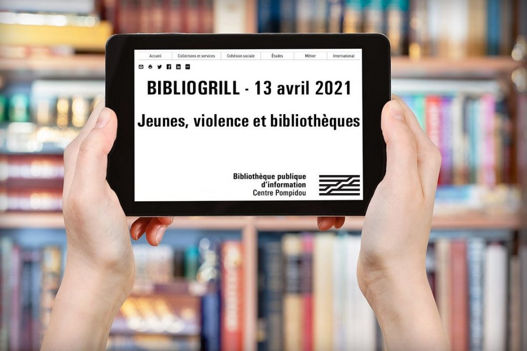 Deux mains tiennent une tablette devant une bibliothèque de livres